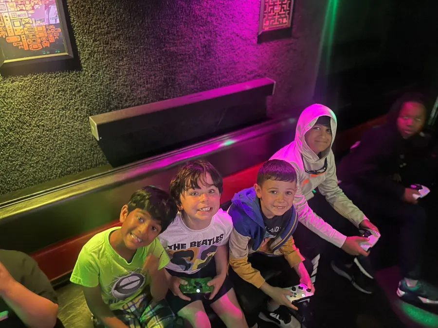Kids grinning up at the camera with controllers in the glowing game truck